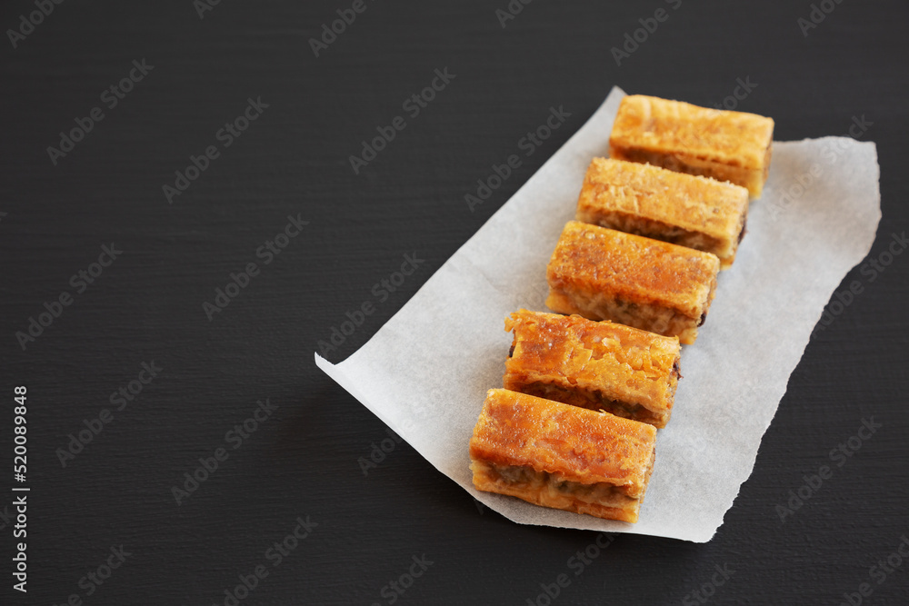 Homemade Baklavas with Honey, Chocolate and Almond on a black background, side view. Copy space. Homemade Baklavas with Honey, Chocolate and Almond on a black background, side view. Copy space.