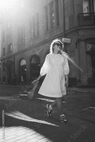 A young woman in a white dress walks through the streets of the city. People, fashion,  lifestyle, travel and vacations concept © maxbelchenko