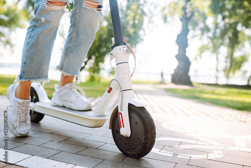 Legs of woman riding electric kick scooter on urban outdoor. Ecological transportation concept.  photo