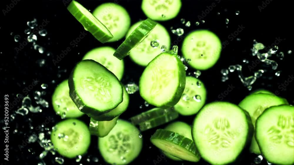 Pieces of fresh cucumbers fly up with drops of water. On a black background.Filmed on a high-speed camera at 1000 fps. Pieces of fresh cucumbers fly up with drops of water. On a black background.Filmed on a high-speed camera at 1000 fps.