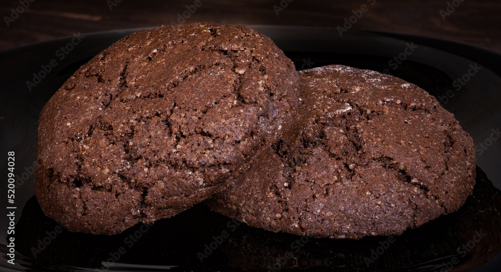 Fototapeta premium Wheat cookies dark with cracks on a black plate