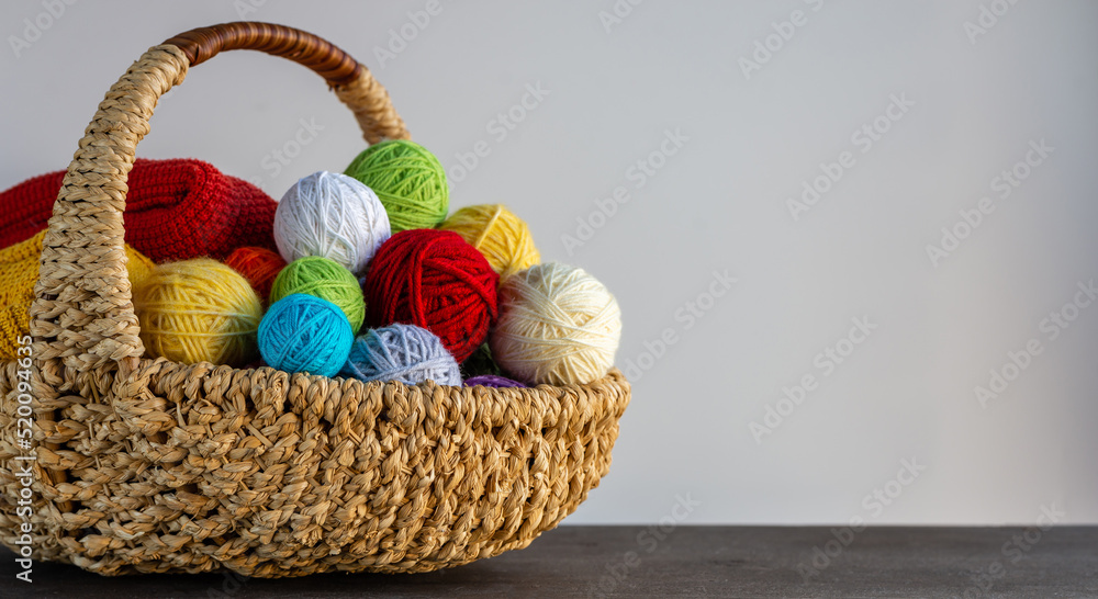 Multi-colored yarn in a basket on the table. Knitting concept. Hobby. Bright background with accessories for knitting. Multi-colored yarn in a basket on the table. Knitting concept. Hobby. Bright background with accessories for knitting.