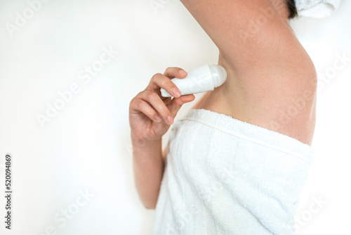 woman in towel after shower uses roll-on deodorant close-up