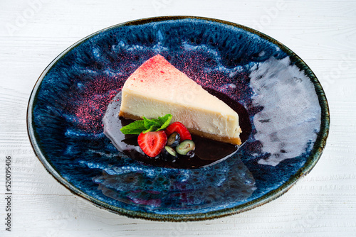 Classical vanilla cheesecake (New York cheesecake) with strawberry on white plate and light background