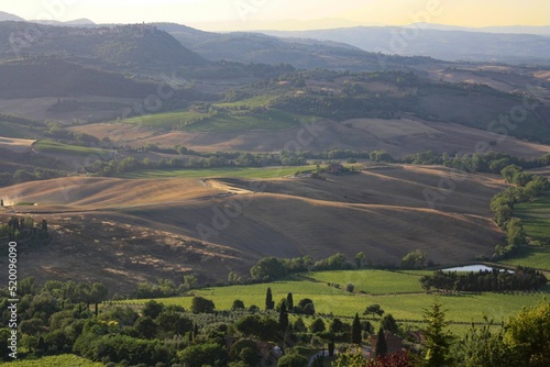  Tuscany landscape at sunrise. Typical for the Tuscan region farmhouse, hills, vineyard. Italy