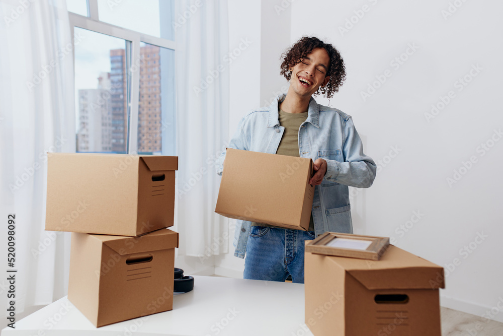guy with curly hair cardboard boxes in the room unpacking Lifestyle guy with curly hair cardboard boxes in the room unpacking Lifestyle