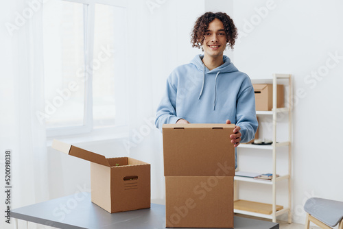 A young man cardboard boxes in the room unpacking interior © SHOTPRIME STUDIO