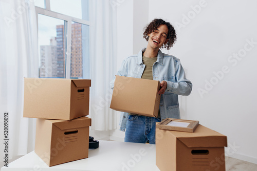 guy with curly hair cardboard boxes in the room unpacking Lifestyle © SHOTPRIME STUDIO