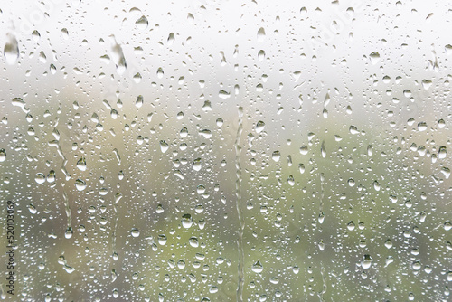 weather background - rain drops and trickles of rain closeup on window glass in heavy rain