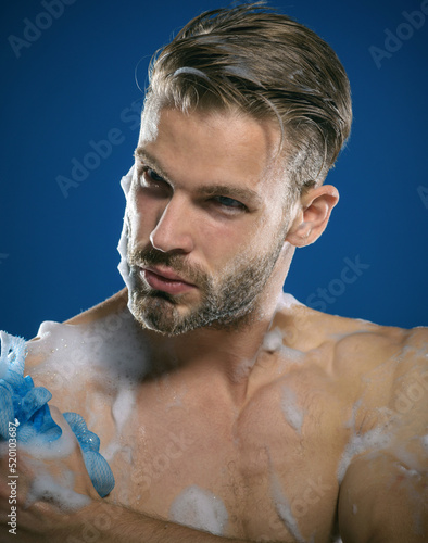 Sexy man taking shower. Unshawen guy is washing body with sponge. Skin care, spa, beauty. Showering.