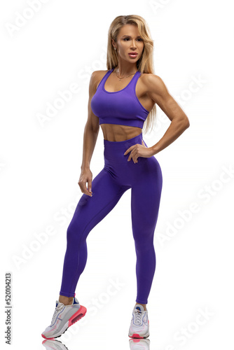 Blonde fit girl in blue leggings and top on a white background in the studio