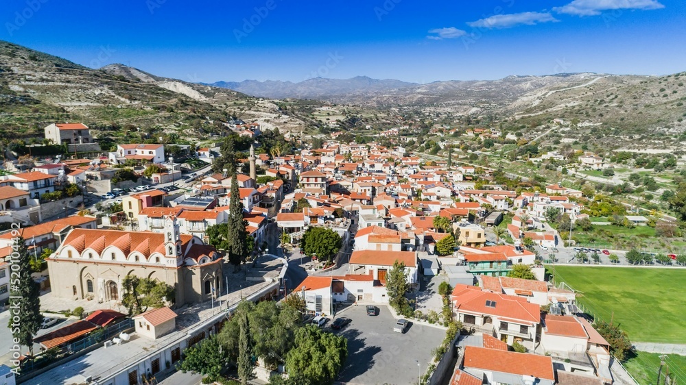 Aerial bird's eye view of Kalavasos village valley, Larnaca, Cyprus. A traditional town with ceramic roof tiles houses, a greek orthodox christian church and muslim mosque around hills from above.	
