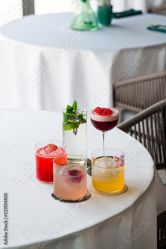 Four colorful summer cocktails in glasses on white table. Assortment of fresh summer drinks. Pink and red sangria cocktails, orange punch cocktail