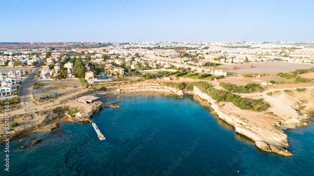 Aerial bird's eye view of Kapparis beach, Protaras, Paralimni, Famagusta, Cyprus. Famous tourist attraction Kaparis bay with boats, sunbeds, restaurant, water sports, people swimming in sea from above