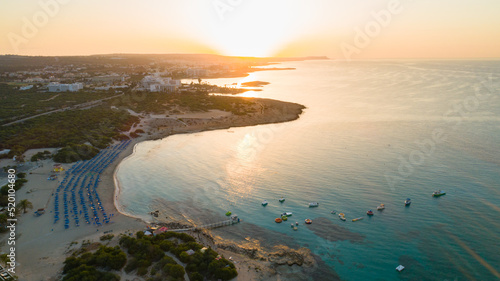 Aerial bird's eye view of Landa beach, Ayia Napa, Famagusta, Cyprus. Landmark tourist attraction golden sand bay at sunrise with boats anchored between Makronissos and nissi in Agia Napa, from above.	