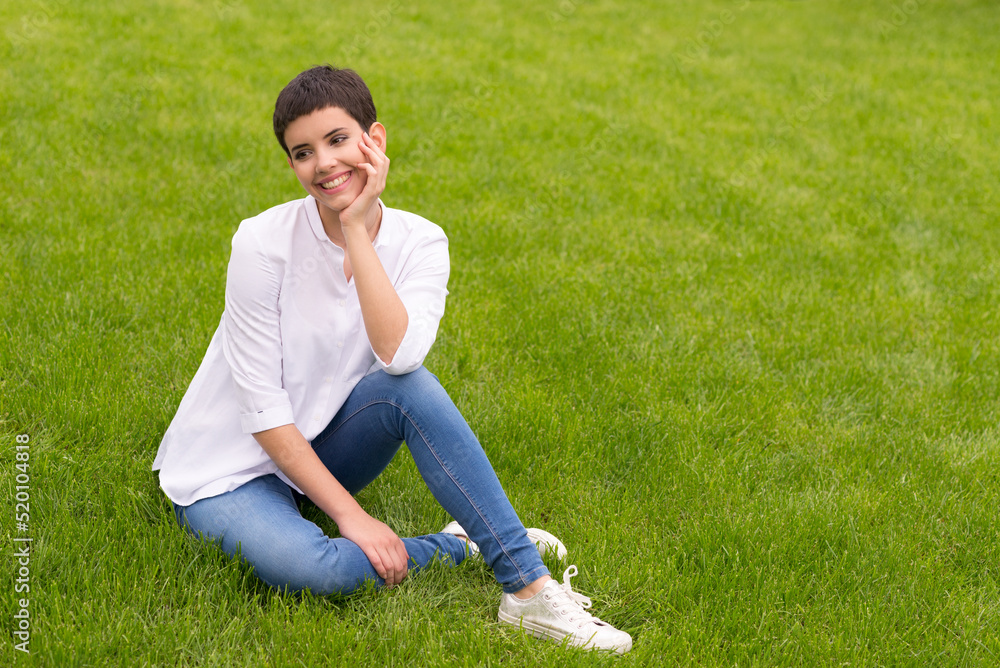 Young woman sitting on the beautiful grass in spring Young woman sitting on the beautiful grass in spring