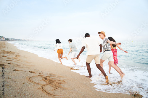 happy young friends group have fun celebrate while jumping and running on the beach at the sunset