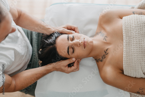 therapist pinching the skin of a young woman's face in a Reiki session