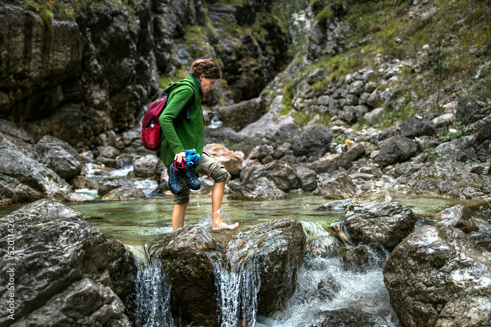 Walking Barefoot Over An Alpine River for a Backpack Adventurous Woman