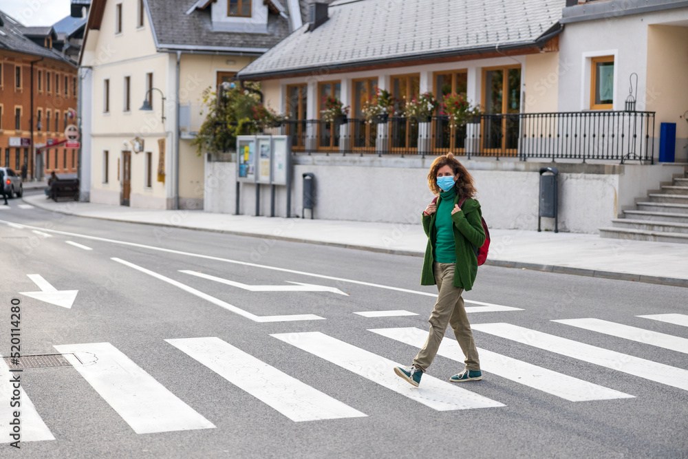 Adult Woman Wearing Face Mask Alone Crossing a Pedestrian Crossing in Town Center