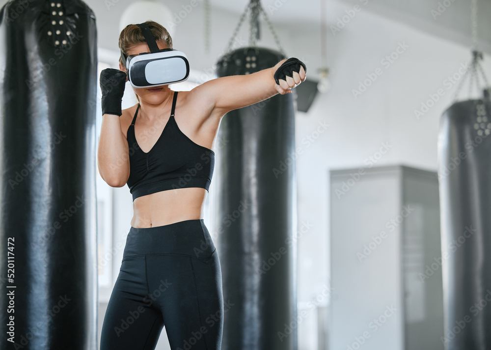 Healthy, fit and active boxing woman with a VR headset to access the metaverse while exercising, training and working out in a gym. Female boxer doing a workout in virtual reality with technology