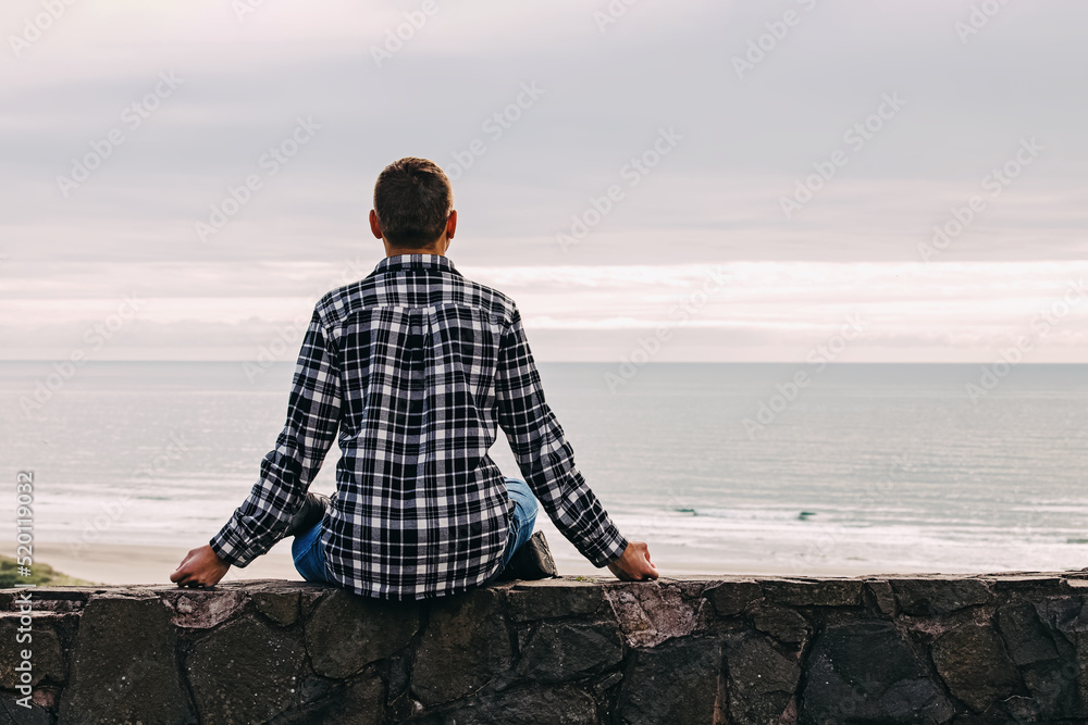 Man in meditation pose looking on the calm ocean
