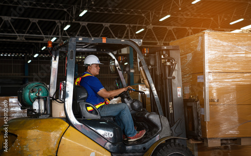 Warehouse worker driver in uniform delivery and loading pallet product by forklift.