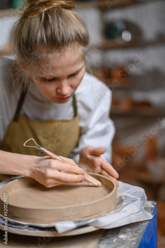 A ceramist makes a plate. Woman in an apron works in a pottery workshop. 