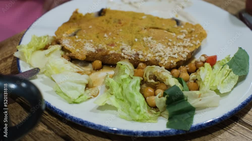 Close-up of woman eating vegan chickpea omelette with mushrooms, lettuce and cherry tomatoes indoors. Slow motion. Healthy organic vegetarian breakfast concept Close-up of woman eating vegan chickpea omelette with mushrooms, lettuce and cherry tomatoes indoors. Slow motion. Healthy organic vegetarian breakfast concept