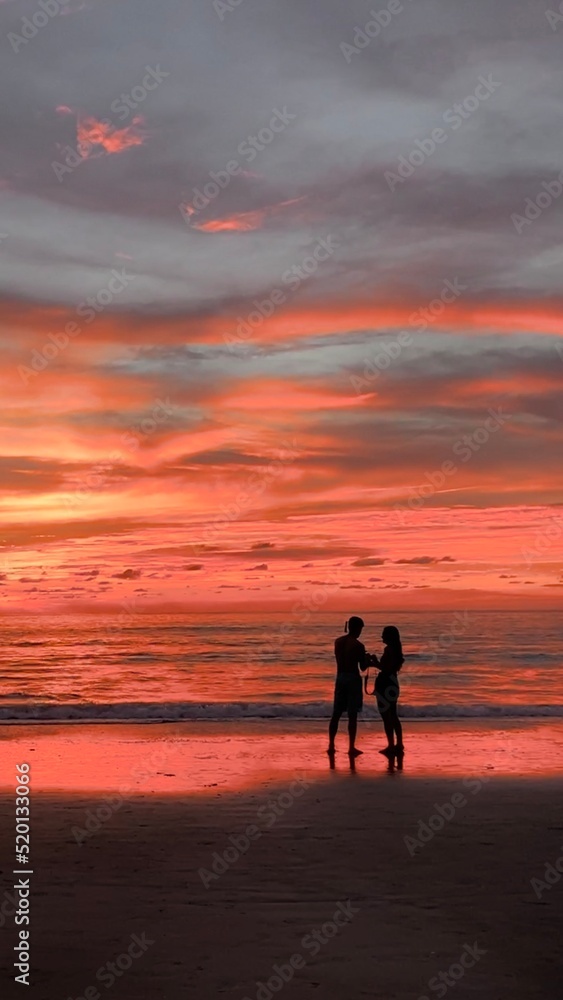silhouettes of woman and man on sunset on the beach