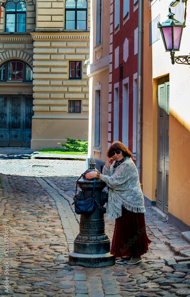 Summer day and woman walking in old street of Riga - the capital of Latvia