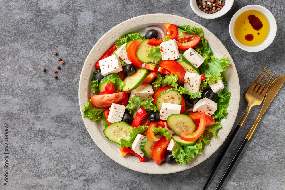 Greek salad of fresh cucumber, tomato, sweet pepper, lettuce, red onion, feta cheese and olives with olive oil. Healthy food. Top view