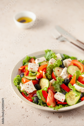 Greek salad of fresh cucumber, tomato, sweet pepper, lettuce, red onion, feta cheese and olives with olive oil. Healthy food
