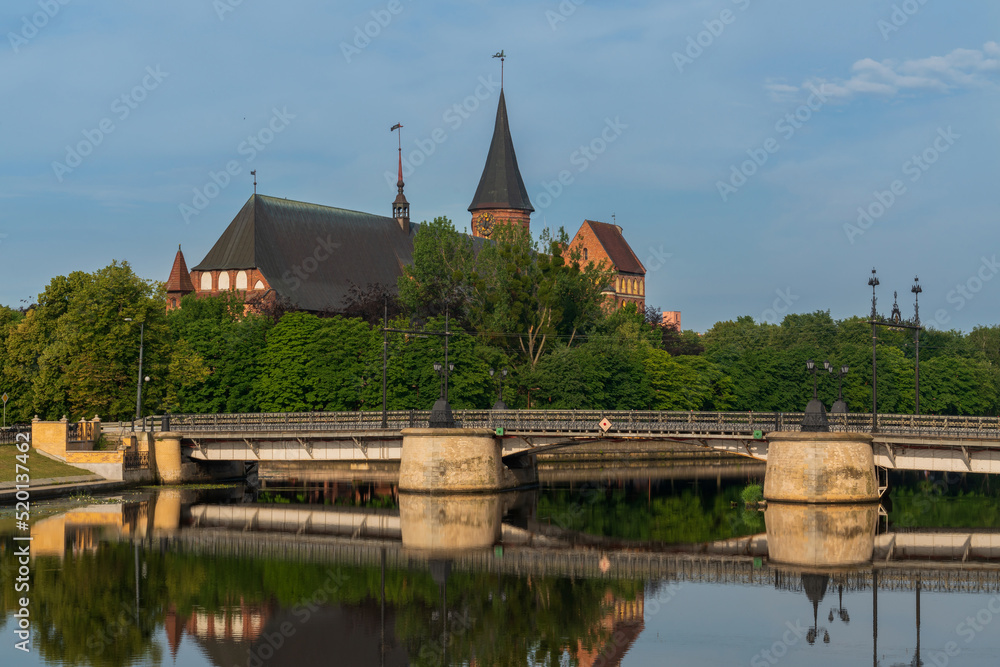 Fototapeta premium View of the Koningberg Cathedral on Immanuel Kant Island against the background of the bridge over the Pregolya River on a sunny summer day, Kaliningrad, Russia
