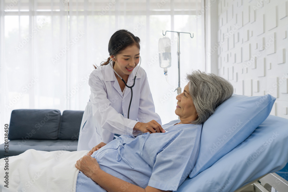Fototapeta premium Senior female patient and doctor. Young asian doctor use a stethoscope to check the heartbeat of the elderly patient.