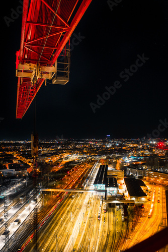 night shot of a crane and urban city with bright lights with long exposure traffic and car lights - berlin by night with the tv tower in the background