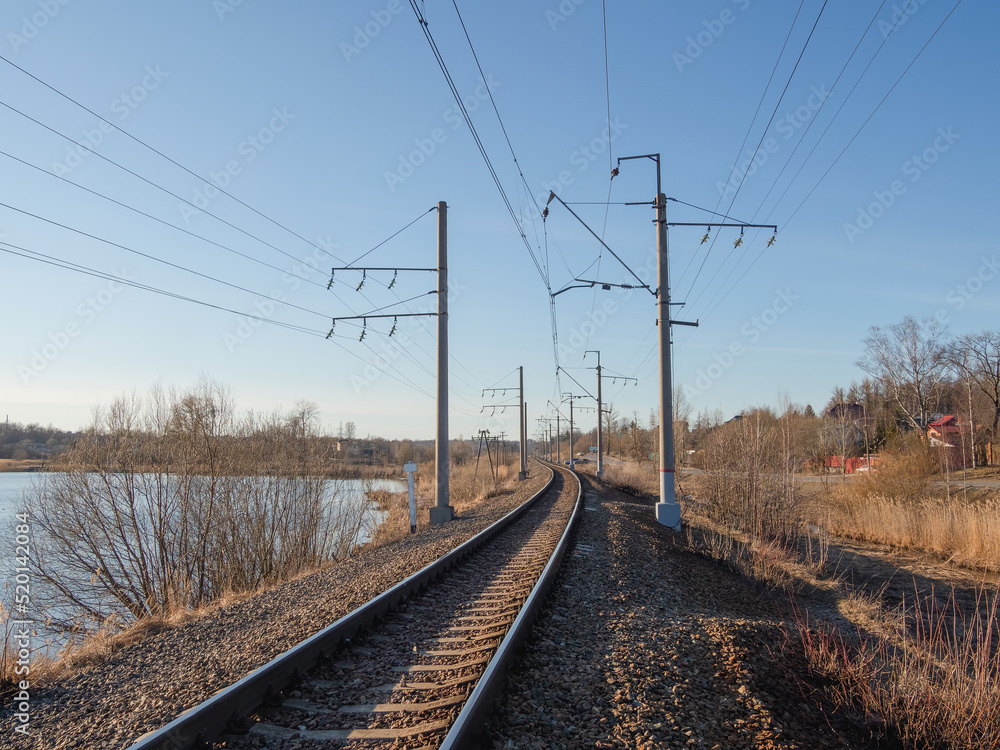 Empty railway track, single rail. Railway track turns and twists between out of focus hills background. Empty rounding and turning single track of railways. Empty railway track, single rail. Railway track turns and twists between out of focus hills background. Empty rounding and turning single track of railways.