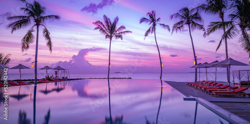 Fantasy dream outdoor infinity swimming pool with fantastic sunset clouds sky. Leisure summer vacation panorama. Travel landscape palm trees umbrellas water reflection. Colorful paradise islands beach