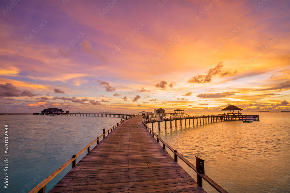 Amazing beach landscape. Beautiful Maldives sunset seascape view. Horizon colorful sea sky clouds, over water villa pier pathway. Tranquil island lagoon, tourism travel background. Exotic vacation
