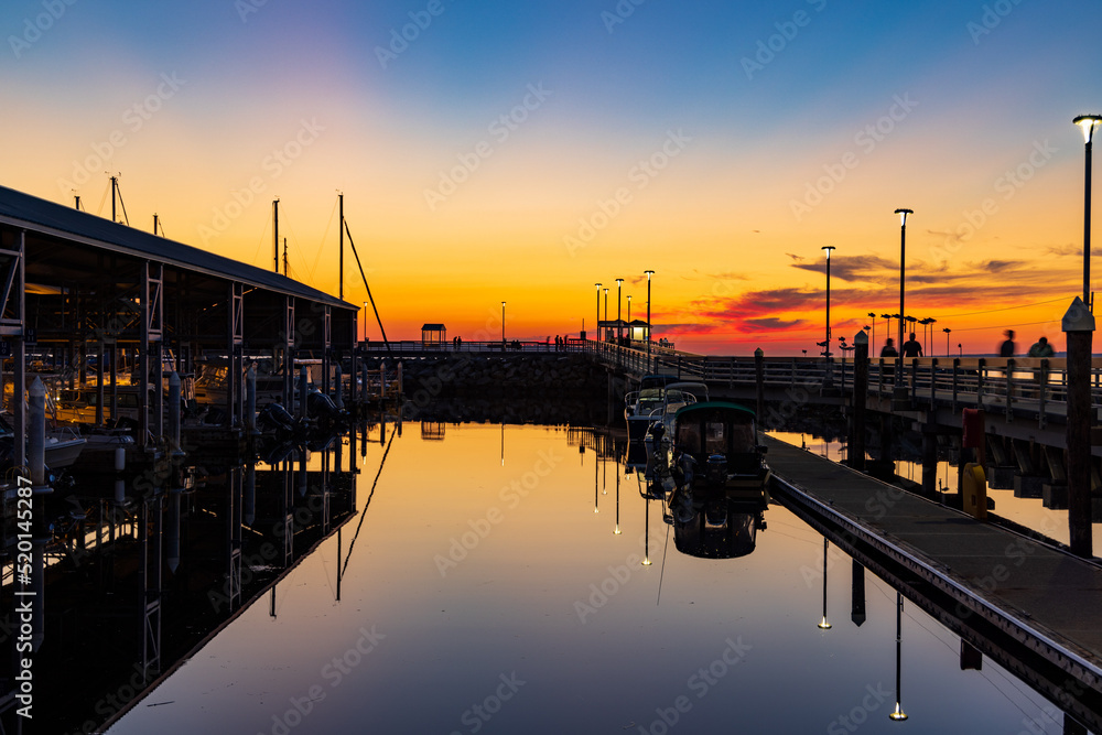 A colorful sunset in the sky with a marina with boats in the foreground