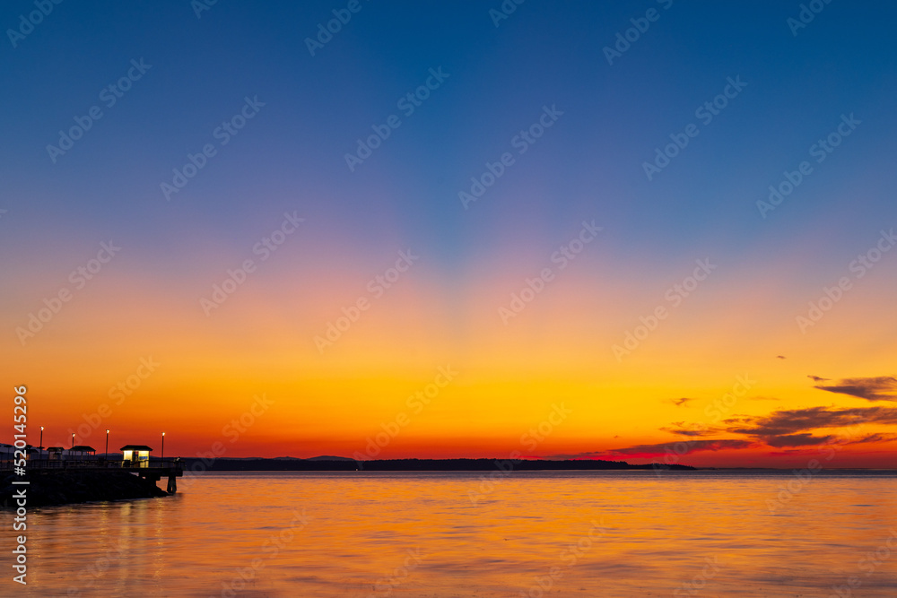 A colorful sunset over Puget Sound with crepuscular rays banding across the sky 