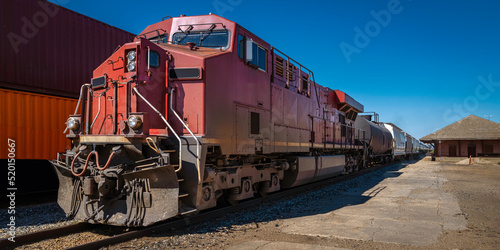 Rustic red cargo train parked in Moose Jaw railway station photo