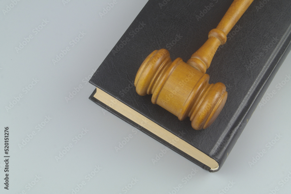 Wooden judge gavel on black legal book on gray background	