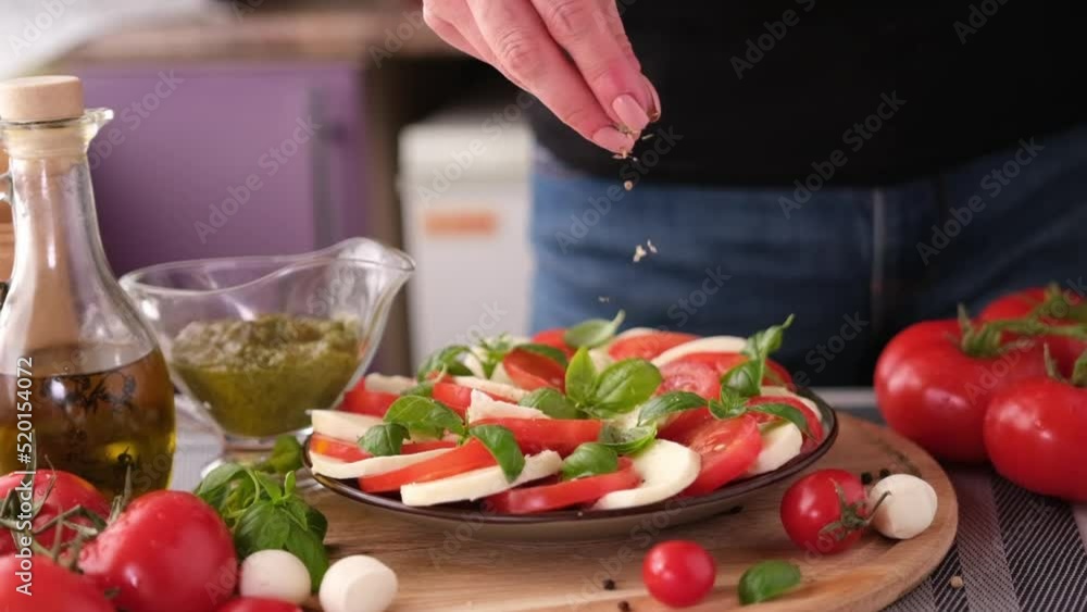 salting caprese salad - mozzarella cheese balls, sliced cherry tomatoes and basil salting caprese salad - mozzarella cheese balls, sliced cherry tomatoes and basil