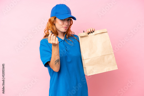 Young caucasian woman taking a bag of takeaway food isolated on pink background making money gesture