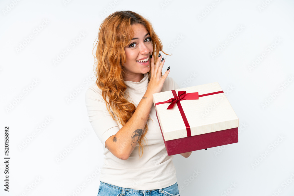 Young caucasian woman holding a gift iso0lated on white background whispering something Young caucasian woman holding a gift iso0lated on white background whispering something