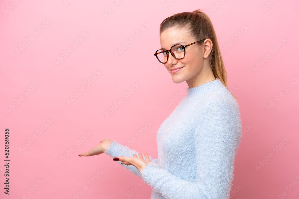 Young caucasian woman isolated on pink background extending hands to the side for inviting to come