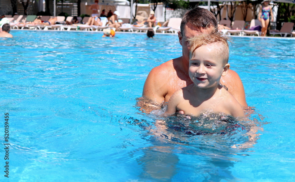 cute fun boy spends fun on a summer day in the pool with his dad at the water park selective focus