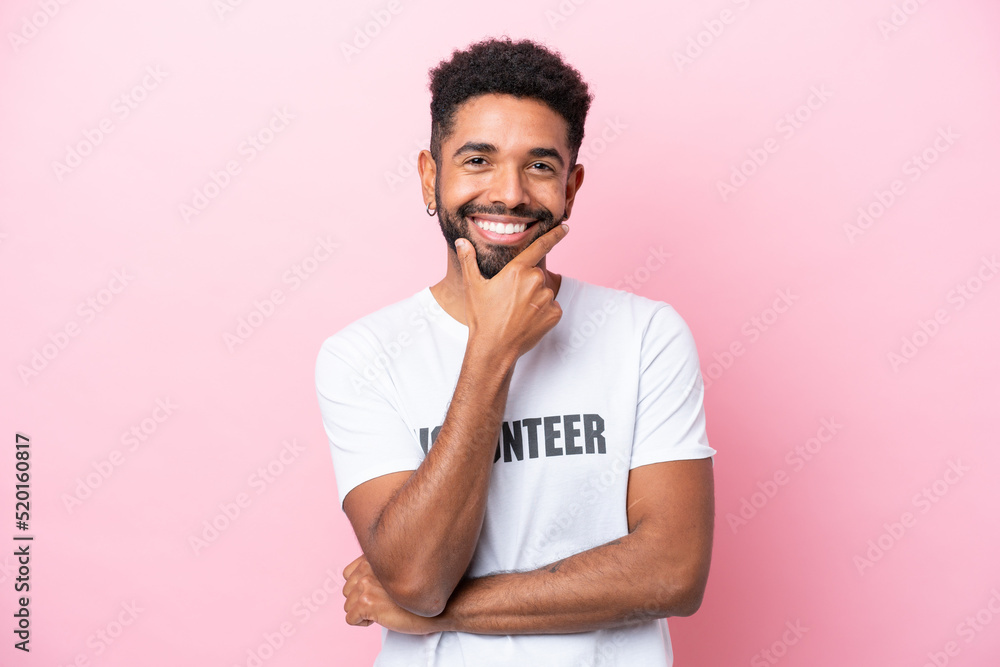 Young volunteer man isolated on pink background happy and smiling Young volunteer man isolated on pink background happy and smiling