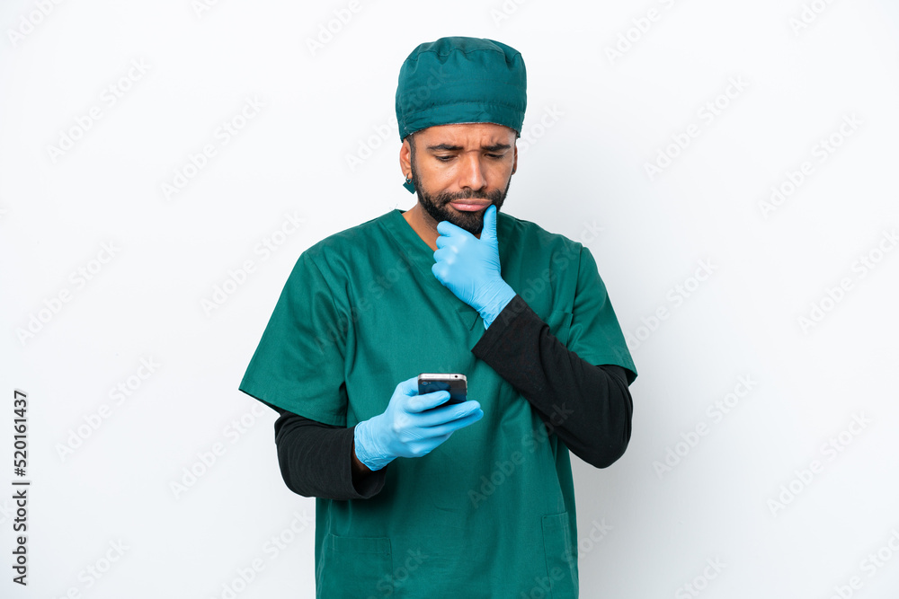 Surgeon Brazilian man in green uniform isolated on white background thinking and sending a message Surgeon Brazilian man in green uniform isolated on white background thinking and sending a message